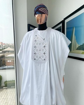 Un motif de broderie en couches blanches et carrées détaille agbada, buba et sokoto