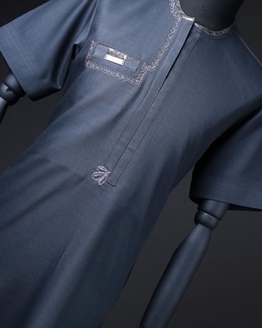 Un col passepoilé bleu marine, argent et noir, une broderie en spirale détaillant le caftan natif.