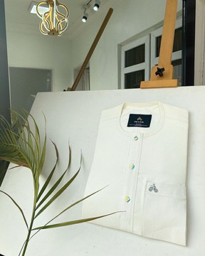Un caftan blanc ivoire avec un bouton en verre abat-jour arc-en-ciel assorti.