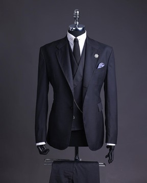 Un costume noir anthracite en tricot à revers cranté, un manteau à double boutonnage et un pantalon.