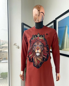 Une encolure passepoilée orange ambre avec un caftan cousu en broderie tête de lion 3D.
