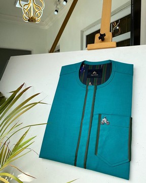 Un caftan sur mesure pour homme vert avec des détails de boutons dorés.
