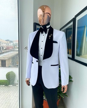 Un costume de smoking blanc avec revers châle en velours noir, un nœud papillon et un pantalon.