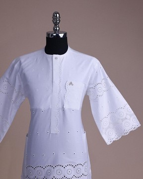 Une dentelle blanche brillante à motifs suisses, un rabat avant avec un caftan africain à motif sur le côté gauche.