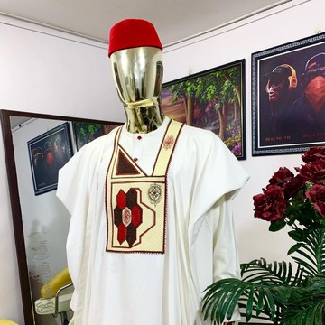 Un agbada blanc avec une casquette Igbo rouge