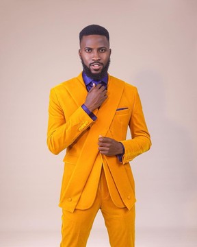 Un costume jaune moutarde "X" à un bouton, une chemise bleu roi, une cravate et un pantalon.