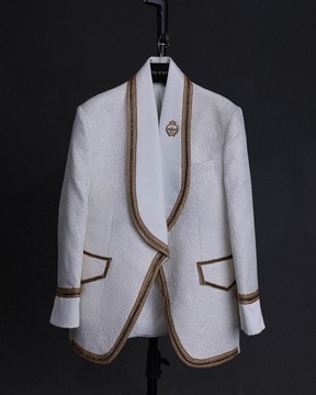 Un jacquard floral blanc ivoire, des garnitures dorées, un costume de smoking à revers châle et poche plaquée