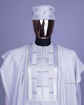 Une broderie blanche aux lignes apparentées, des cristaux Swarovski argentés détaillant l'agbada