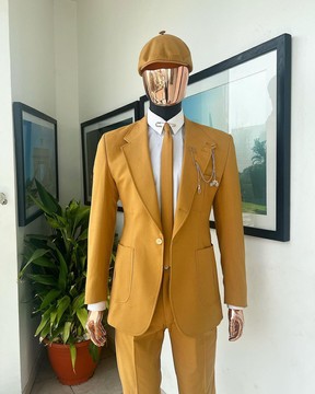 Une veste en lin jaune moutarde, une cravate coupe slim, un pantalon Gurkha, un pantalon et un chapeau